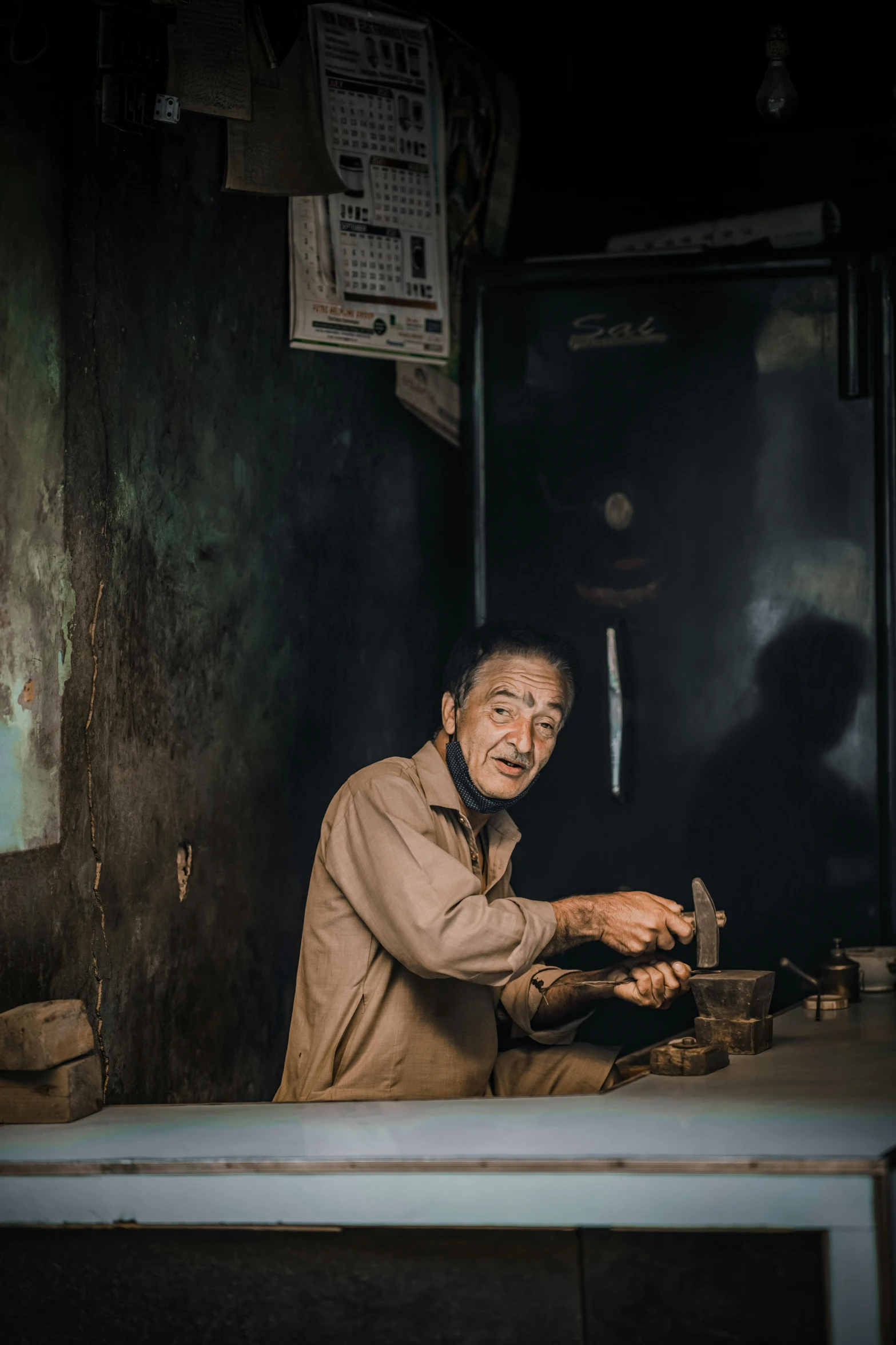 a man sitting at a table with a knife in his hand, a picture, inspired by Steve McCurry, pexels contest winner, old charismatic mechanic, an arab standing watching over, old shops, smiling man