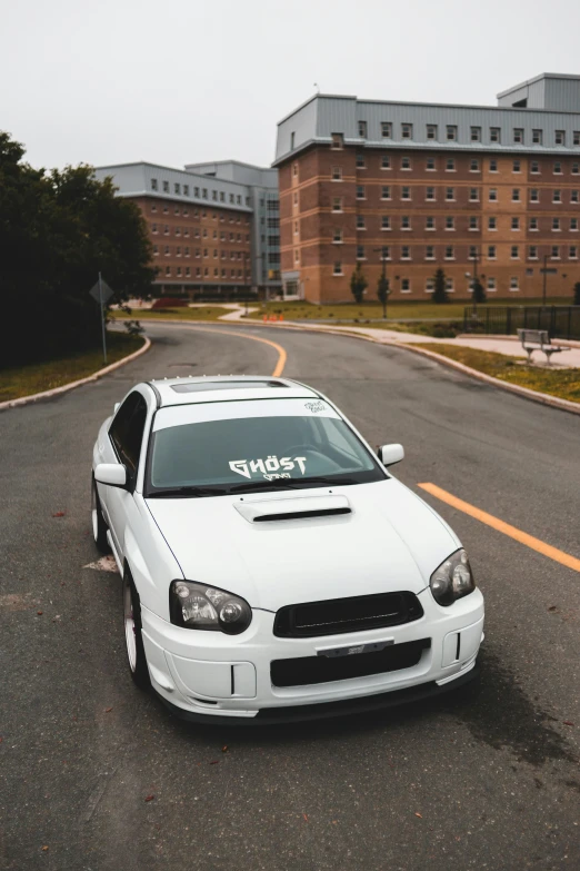 a white car parked on the side of a road, inspired by Michael Gustavius Payne, pexels contest winner, extreme shitty car mods, subaru, at college, front portrait