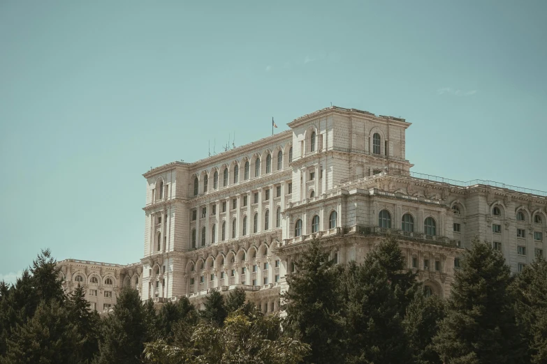 a large building surrounded by trees on a sunny day, a photo, pexels contest winner, neoclassicism, romanian heritage, with stalinist style highrise, demna gvasalia, from of thrones