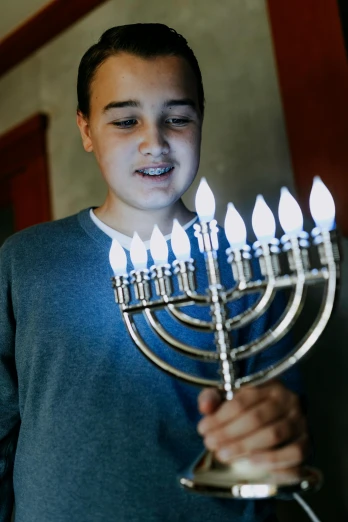 a young boy lighting a menorah with candles, 💣 💥💣 💥, leds, teenager, family friendly
