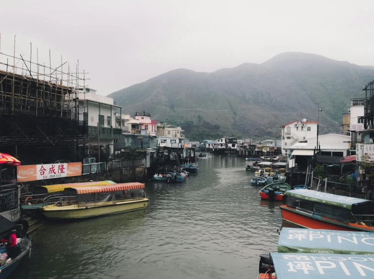 a river filled with lots of boats next to tall buildings, pexels contest winner, mingei, trending on vsco, misty ghost town, mountains and ocean, 🦩🪐🐞👩🏻🦳