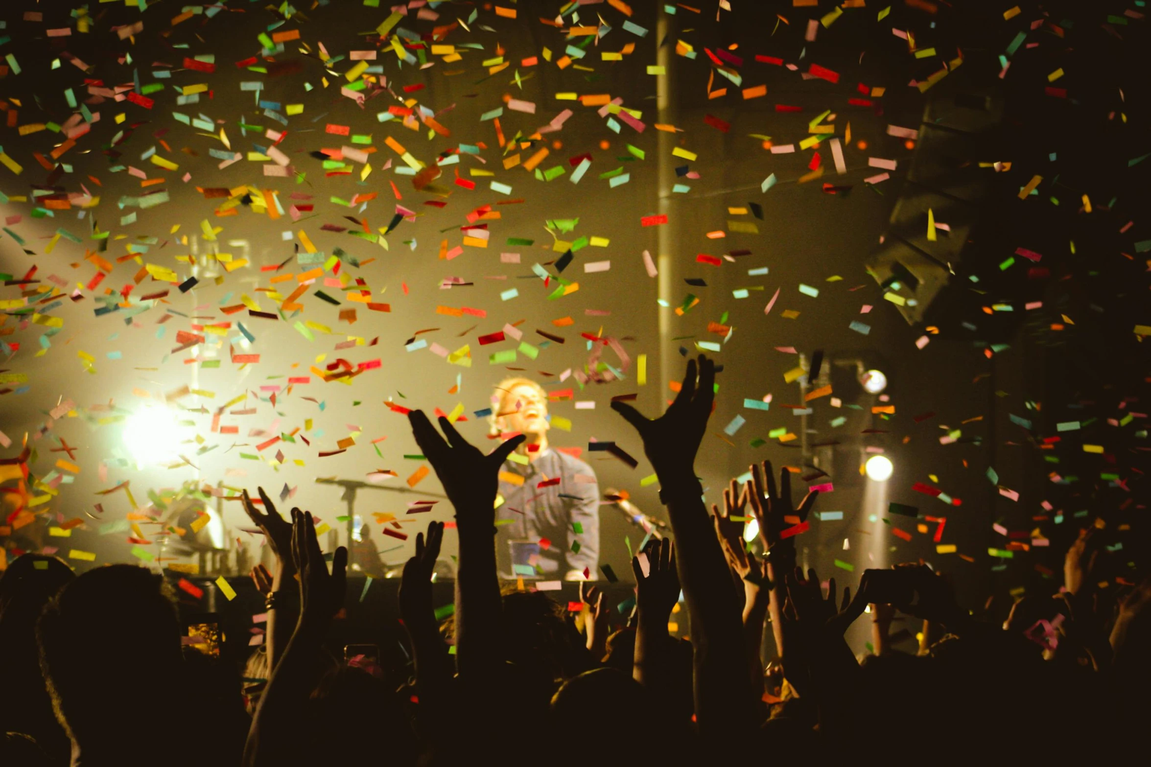 a man standing on top of a stage surrounded by confetti, pexels, jamie campbell bower, full of colours, leaves in the air, lily allen