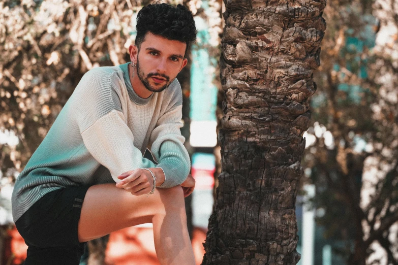 a man sitting on top of a palm tree, pexels contest winner, sweater, young spanish man, non binary model, avatar image