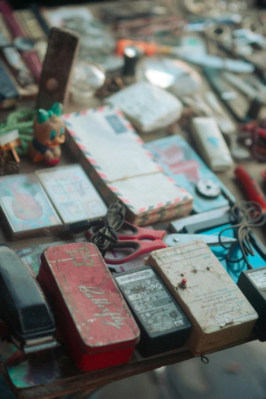 a table topped with lots of assorted items, an album cover, trending on unsplash, assemblage, batteries not included, shanghai, wooden art toys, scrapyard