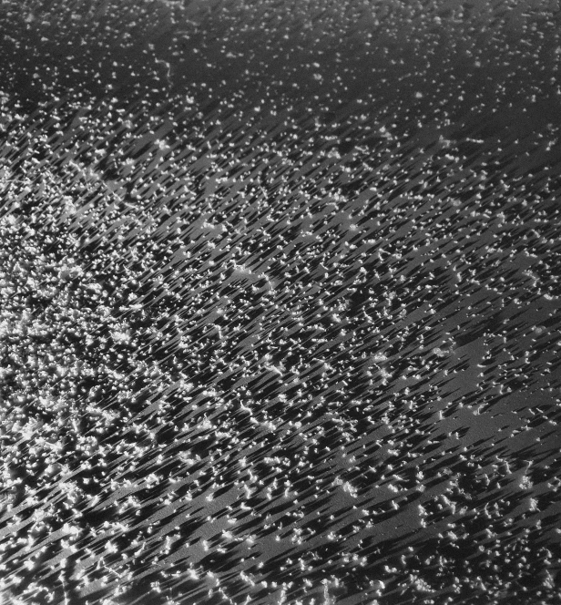 a black and white photo of a person on a surfboard, inspired by Vija Celmins, unsplash, kinetic pointillism, wet aslphalt road after rain, abstract detail, at evening during rain, metallic surface