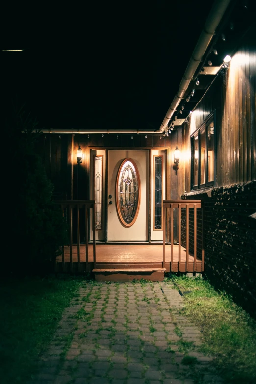 a house that is lit up at night, wood door, outdoors setting, dark hallway, western setting