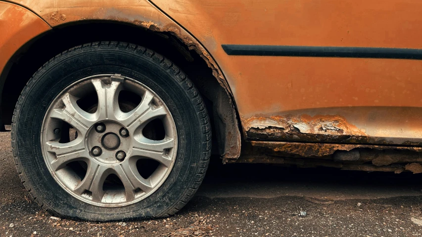 a rusted car parked on the side of the road, detailed alloy wheels, profile image, getty images, brown