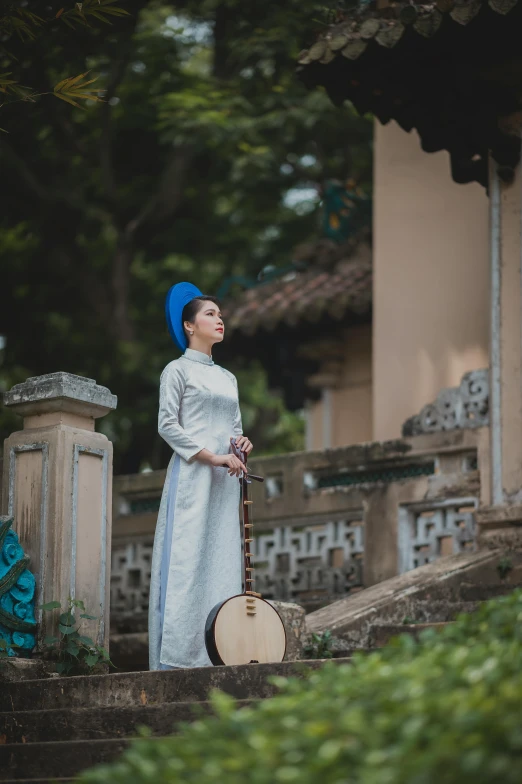 a woman in a white dress is holding a guitar, inspired by Gu An, happening, vietnamese temple scene, wearing a blue qipao dress, ( ( theatrical ) ), square