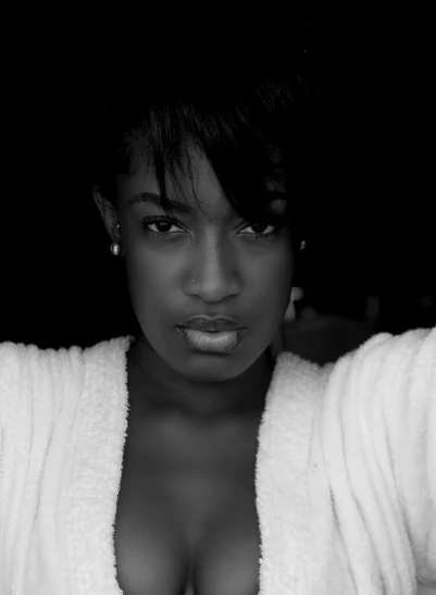 a black and white photo of a woman in a bathrobe, by Lily Delissa Joseph, very dark brown skin!, confident smirk, black young woman, uploaded