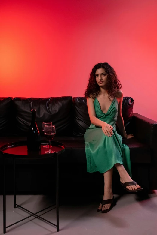 a woman in a green dress sitting on a couch, an album cover, inspired by Nan Goldin, pexels contest winner, serial art, angela sarafyan, full body potrait holding bottle, high quality photo, evening mood