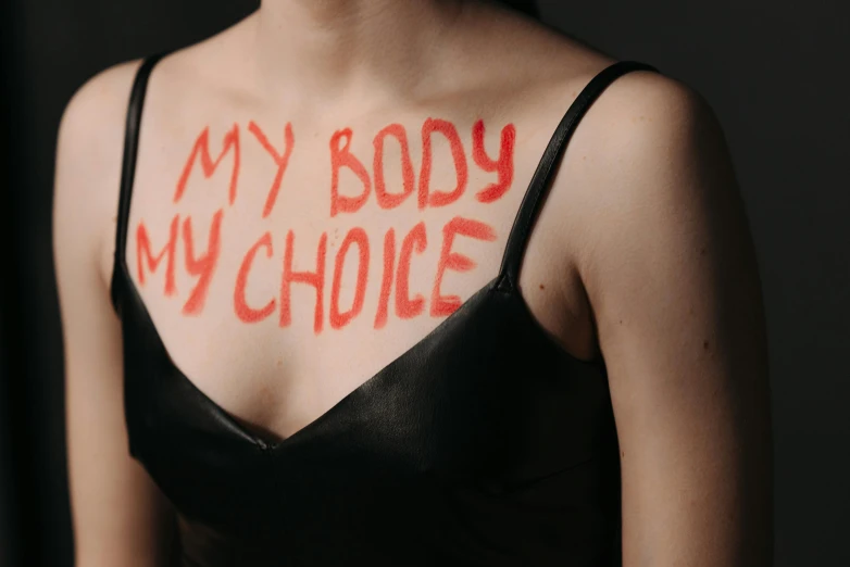 a woman with the words my body my choice painted on her chest, trending on pexels, cruelty, skins, picture, body format