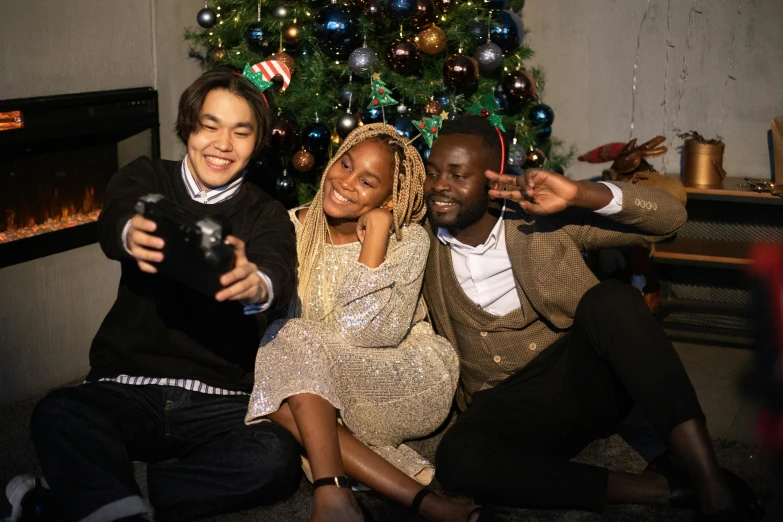 a group of people sitting next to a christmas tree, a picture, pexels, happening, black people, avatar image, mobile gimball camera, actor