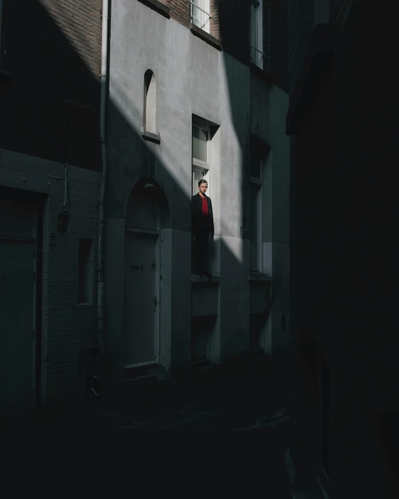 a person standing in the doorway of a building, an album cover, unsplash contest winner, androgynous vampire, dark neighborhood, ignant, the man looked up