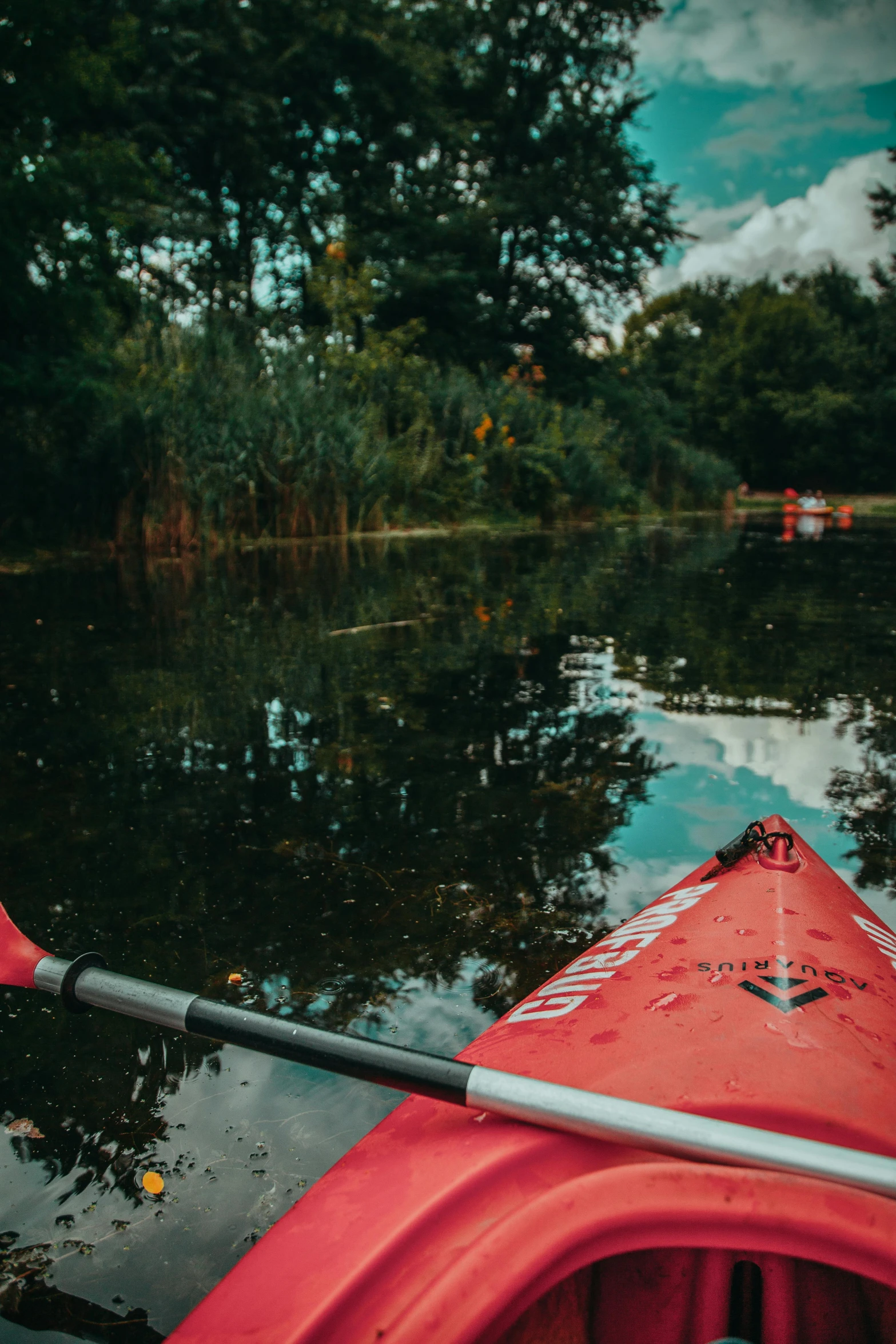 a red kayak sitting on top of a body of water, lush surroundings, thumbnail, explore, low - angle shot