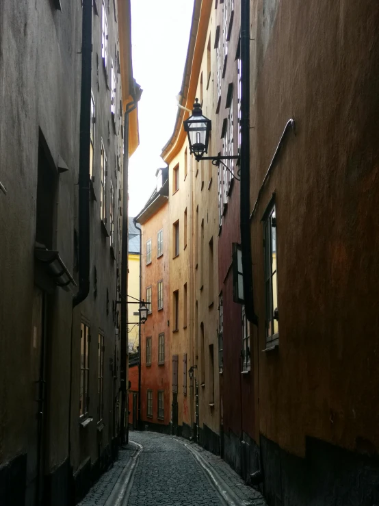 a narrow cobblestone street in an old european city, by Tom Wänerstrand, pexels contest winner, stockholm, light - brown wall, view from the side”, colorful caparisons