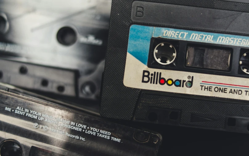 a close up of a cassette on a table, an album cover, unsplash, graffiti, vhs artefacts, bill gold, billboard, celluloid