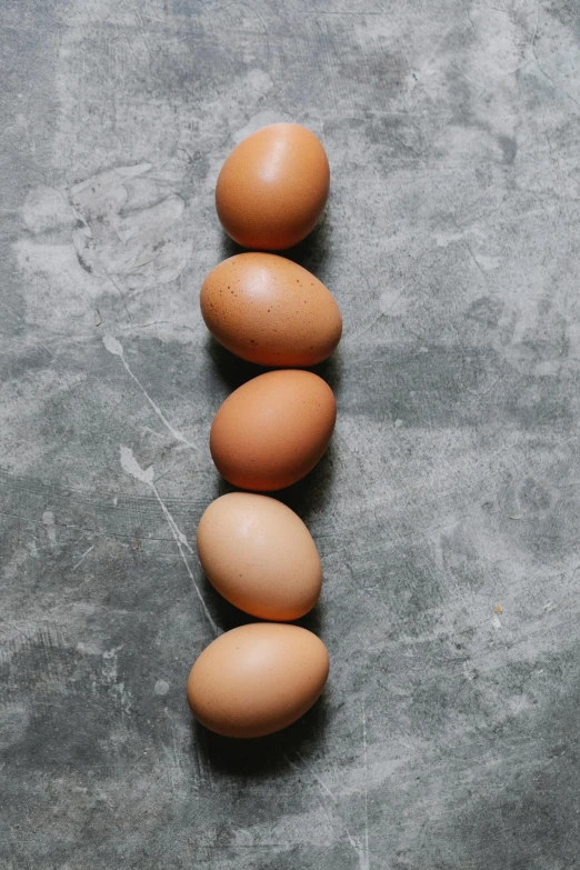 a number of eggs arranged in a row on a table, by Jessie Algie, unsplash, portrait of tall, on grey background, chicken, ballard