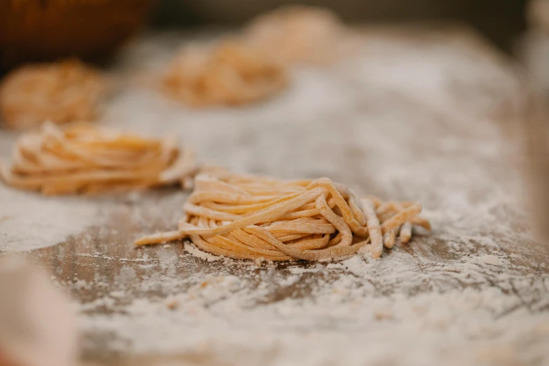 a pile of pasta sitting on top of a table, by Daniel Lieske, trending on pexels, flour dust, award - winning crisp details, ropes, vanilla