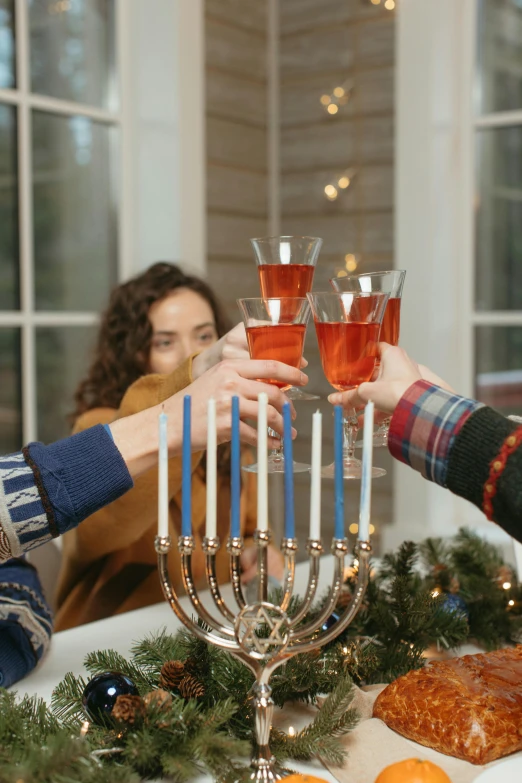 a group of people standing around a table with a menorah, holiday season, holding a drink, gen z, vine