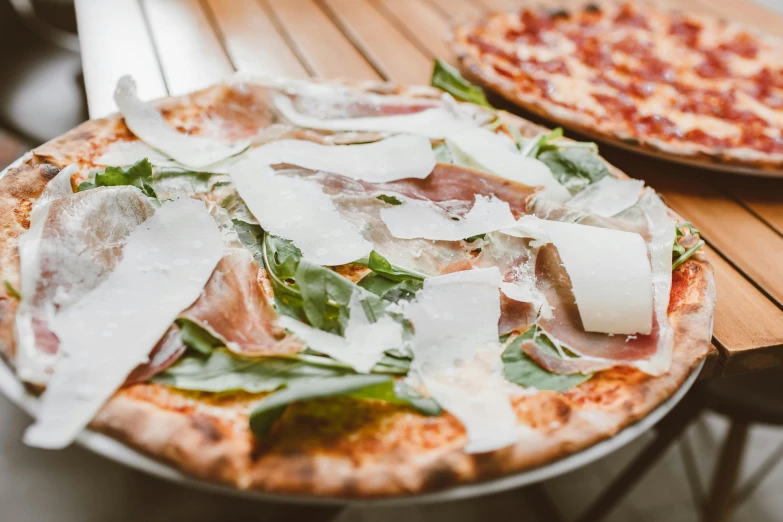 a couple of pizzas sitting on top of a wooden table, ivy's, covered in white flour, exterior shot, graphic print