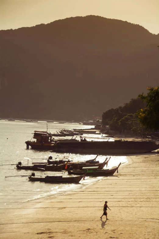 a person walking on a beach next to boats, sumatraism, golden hours, on location, fully covered, view