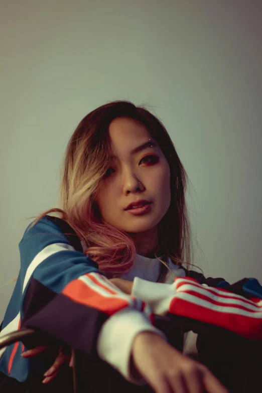 a woman sitting on top of a chair next to a wall, an album cover, inspired by Feng Zhu, unsplash, hyperrealism, wearing a track suit, beautiful young asian woman, headshot, concert