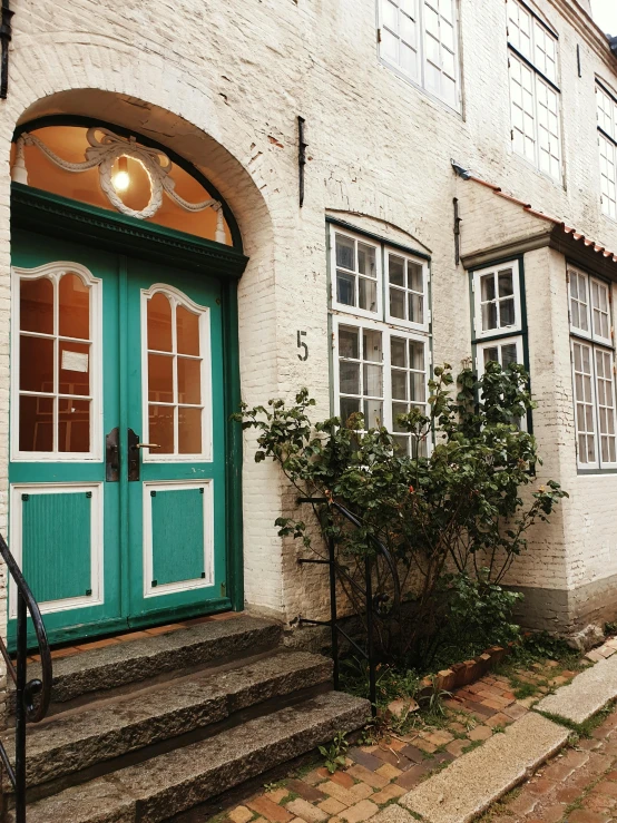 a green door sitting on the side of a building, pexels contest winner, heidelberg school, teal white gold color palette, scandinavian style, thumbnail, multiple stories