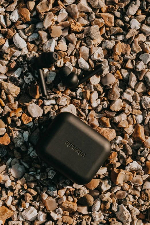 a black case sitting on top of a pile of rocks, by Eden Box, unsplash, sleek metal ears, beaching, pods, thumbnail