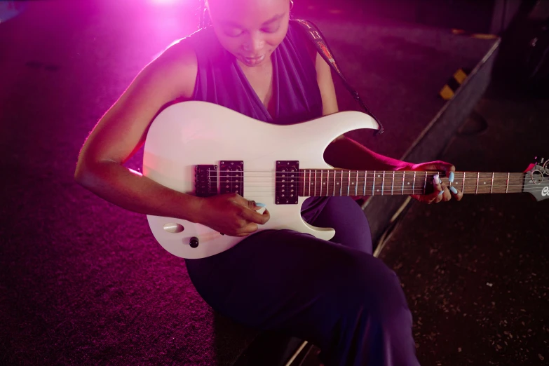 a woman sitting on a bench playing a guitar, inspired by Ray Parker, pexels contest winner, happening, white and purple, ( ( dark skin ) ), electric guitar, bottom angle