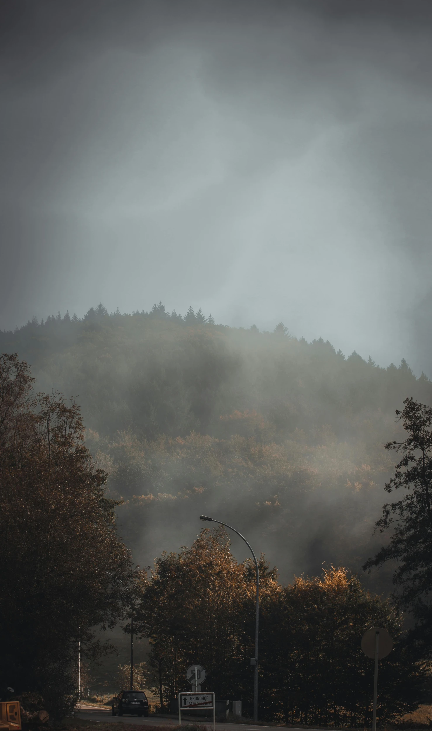 a street with a mountain in the background, an album cover, inspired by Elsa Bleda, unsplash contest winner, tonalism, ominous! landscape of north bend, autumn light, today\'s featured photograph 4k, light fogged