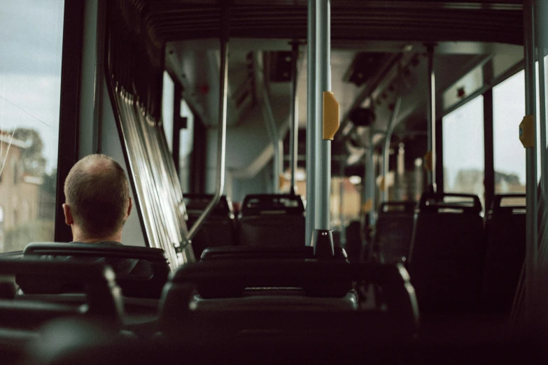 a man sitting on a bus looking out the window, by Carey Morris, pexels contest winner, videogame still, buses, inside a grand, carson ellis