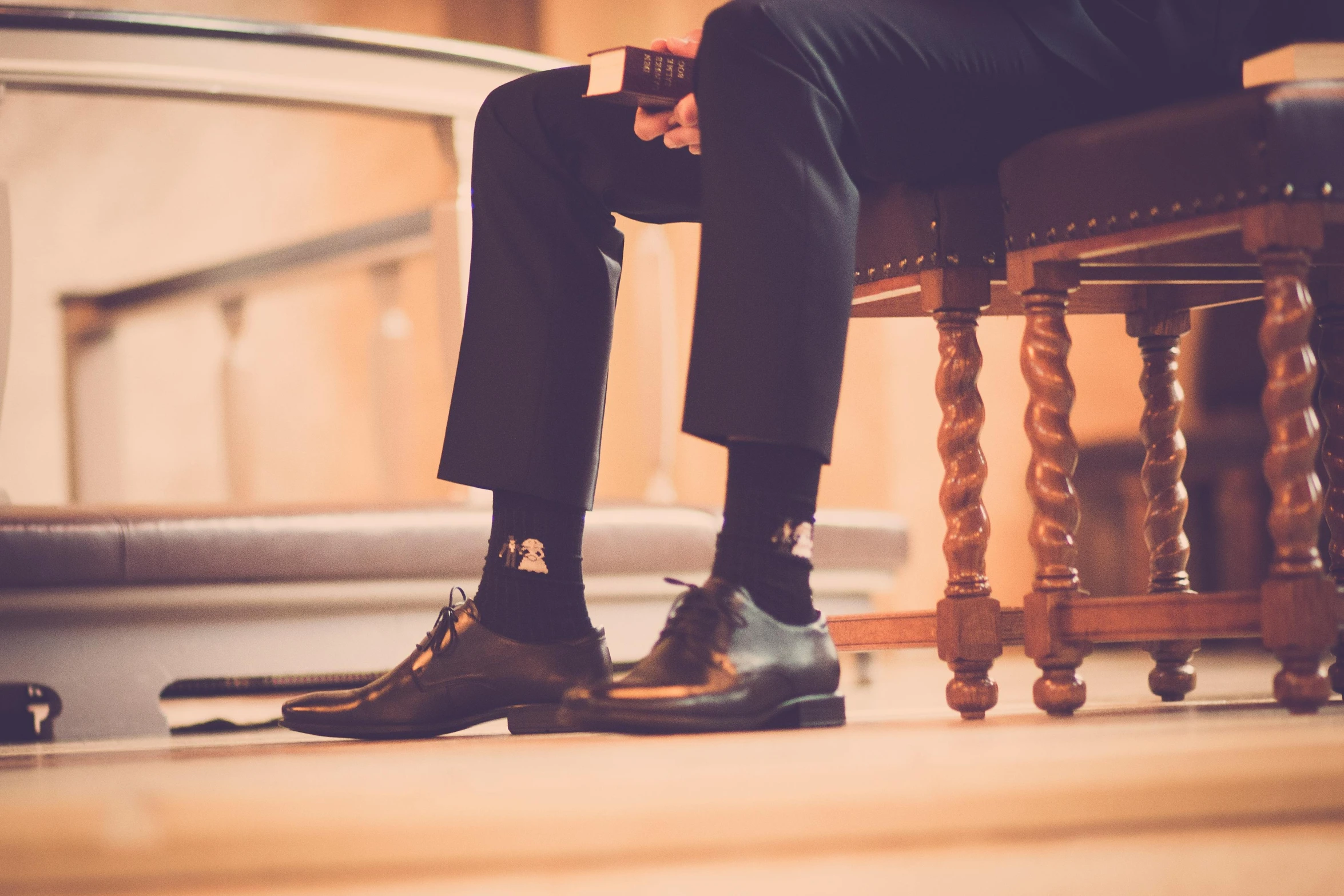 a man in a suit and tie sitting on a chair, by Romain brook, trending on unsplash, silk shoes, in church, high details, unedited