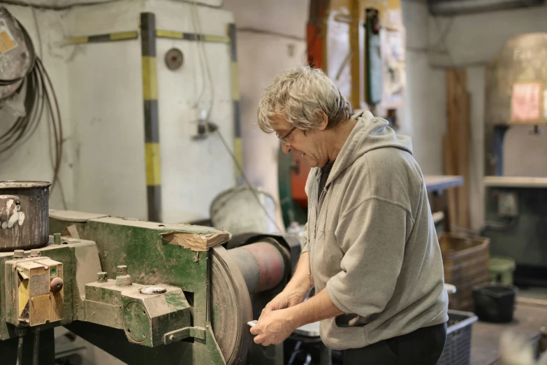 a man working on a machine in a workshop, fiona staples, pitch bending, profile image, heavy grain