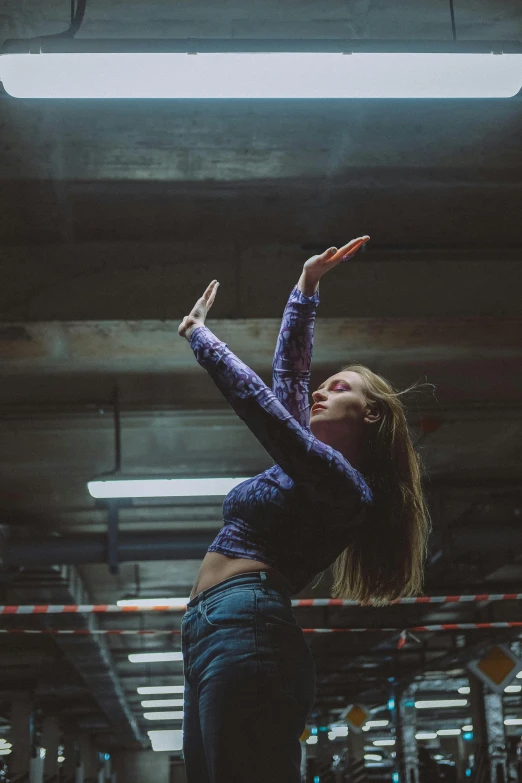a woman standing in the middle of a parking garage, an album cover, inspired by Elsa Bleda, pexels contest winner, renaissance, fists in the air, wearing a crop top, dance scene, performing on stage