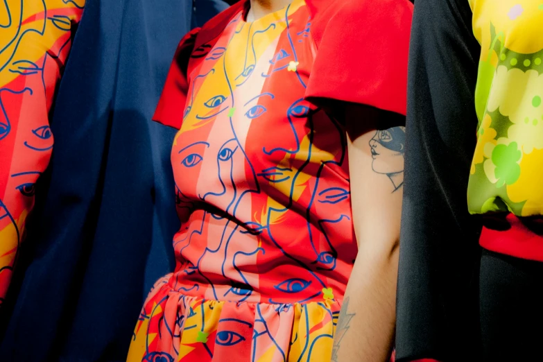 a woman standing in front of a rack of clothes, a cartoon, trending on pexels, fauvism, blue and red tattoo, fashion week backstage, details faces, wearing red and yellow hero suit