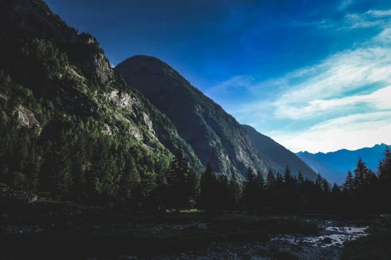 a river running through a lush green valley, by Sebastian Spreng, pexels contest winner, chamonix, dimly - lit, blue and clear sky, standing in front of a mountain