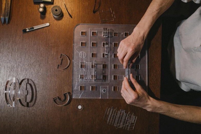 a person working with tools on a table, an album cover, inspired by Josef Čapek, unsplash, game board, 3d printed, ignant, edible