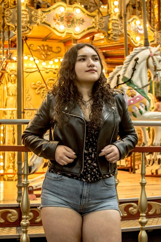 a woman standing in front of a carousel, wearing a leather jacket, hot topic, asher duran, slightly overweight