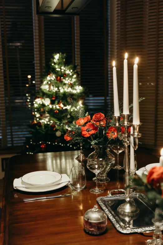 a dining room table with a christmas tree in the background, pexels contest winner, romanticism, side lights, evening light, decorated with flowers, indoor scene