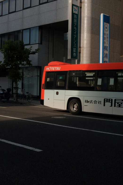 a red and white bus driving down a street, by Sengai, unsplash, sōsaku hanga, grey orange, 8 l, on ground, 2077