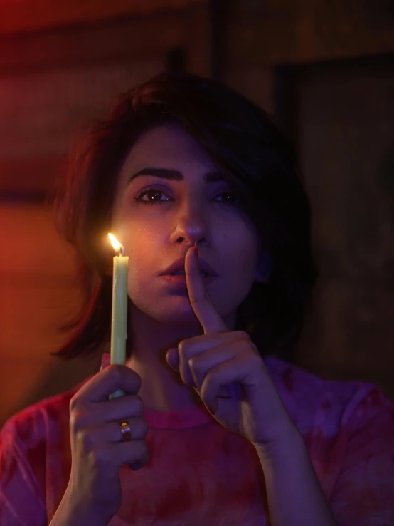 a woman holding a lit candle in front of her face, an album cover, inspired by Elsa Bleda, trending on pexels, mahira khan as a mage, lesbians, woman smoking cigarette, movie still frame