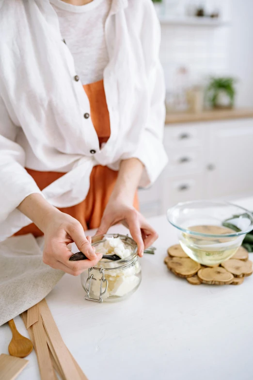 a woman standing in a kitchen preparing food, trending on pexels, process art, inside a glass jar, wearing white silk robe, butter, promo image