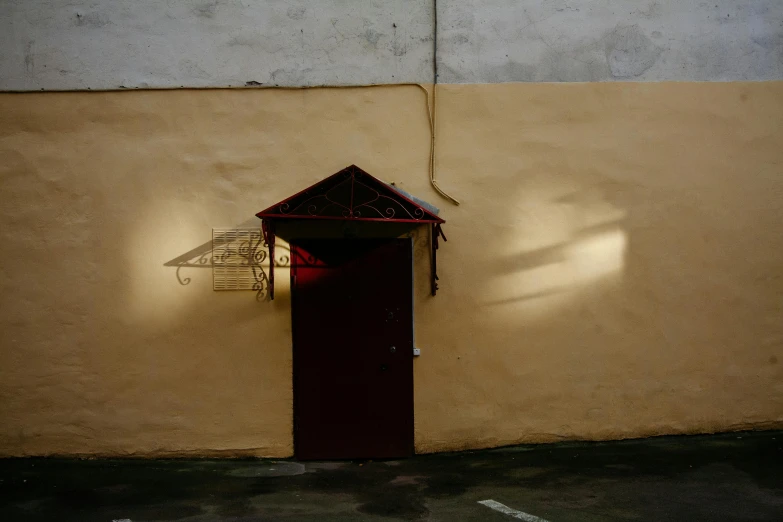 a red door in front of a yellow wall, by Attila Meszlenyi, bengal school of art, shadowy lighting, yellow awning, prison, photo for a store