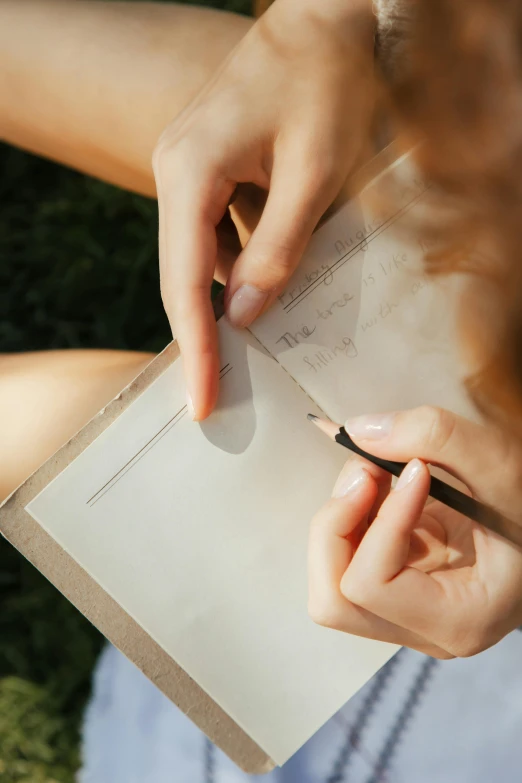 a close up of a person writing on a piece of paper, an album cover, pexels contest winner, sunny summer day, parchment paper, woman, thin lines