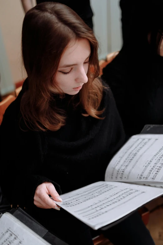 a woman sitting on a chair holding a sheet of music, concentration, student, opus francigenum, in depth