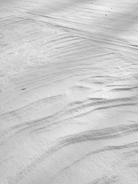 a man riding skis down a snow covered slope, inspired by Edward Weston, land art, sand texture, summer 2016, lena oxton, sinuous