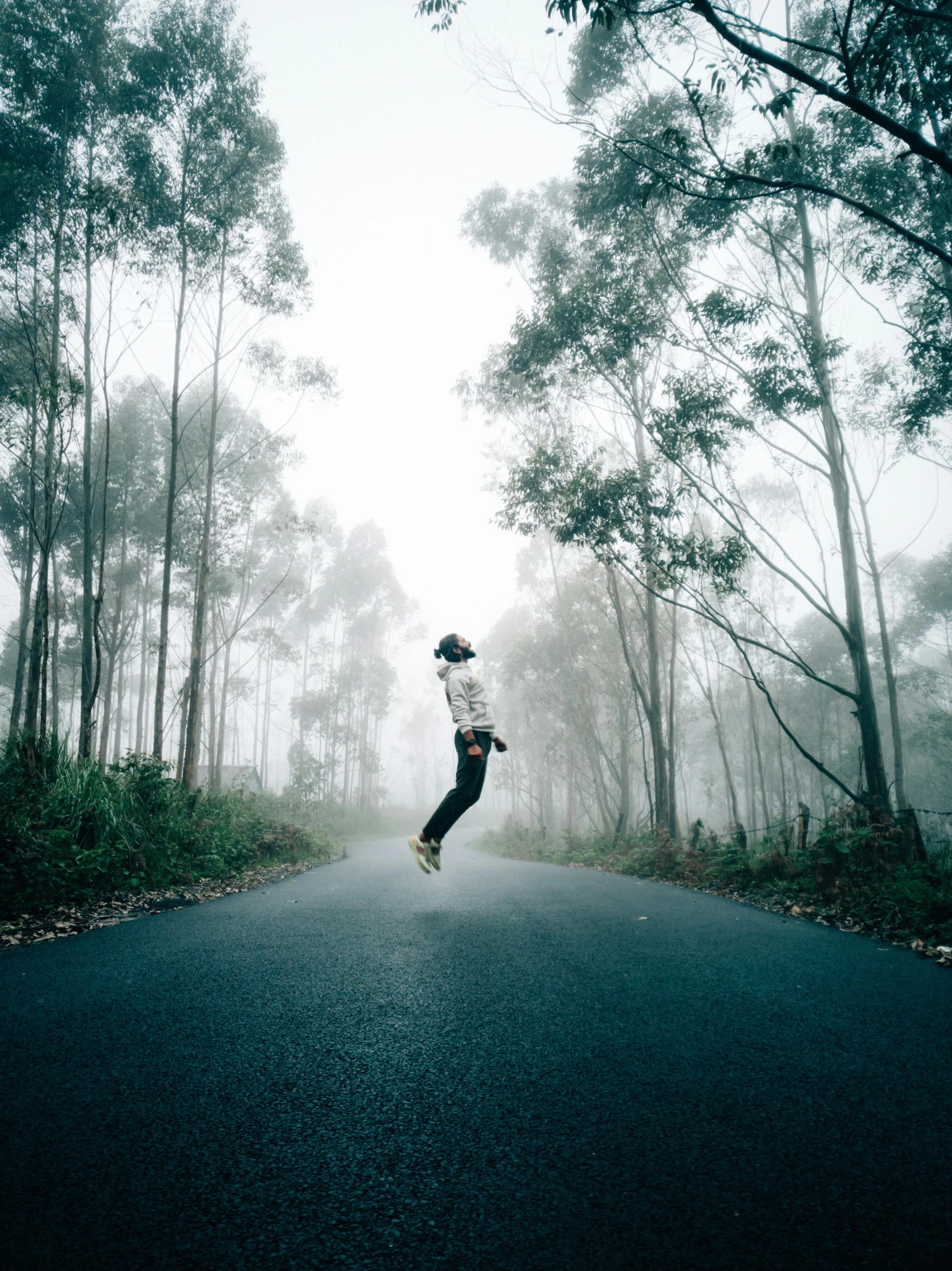 a person jumping in the air in the middle of a road, a picture, pexels contest winner, foggy forrest backdrop, nostalgic 8k, college, over the tree tops