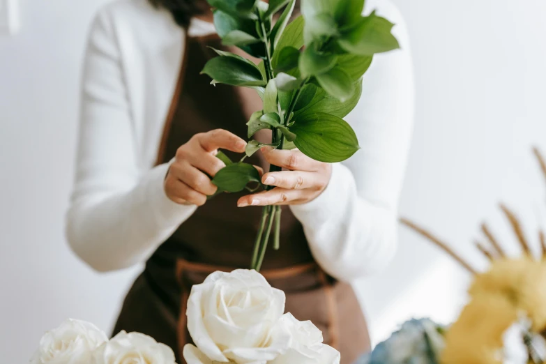 a woman holding a bunch of flowers in her hands, pexels contest winner, arts and crafts movement, browns and whites, crafting, minimalistic aesthetics, roses