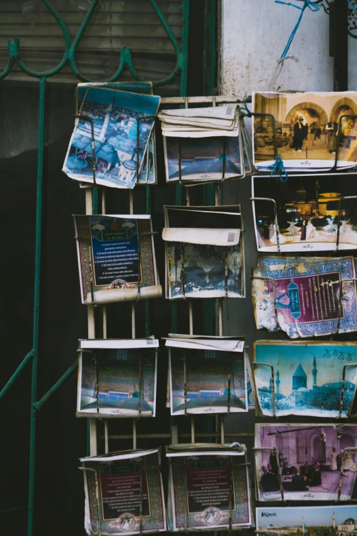 a bunch of pictures hanging on the side of a building, shelves filled with tomes, jerusalem, black and teal paper, trending photo