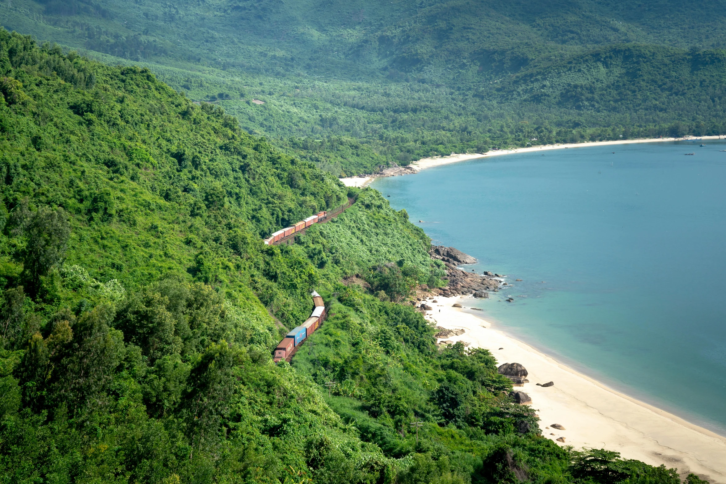 a large long train on a steel track near a body of water, hurufiyya, in style of lam manh, lush paradise, thumbnail, overlooking the beach